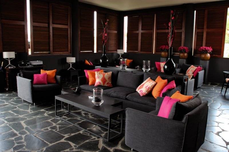 Hotel-Lounge im Van der Valk Kontiki Beach Resort Curaçao mit schwarzen Möbeln, bunten Kissen und Vasen.