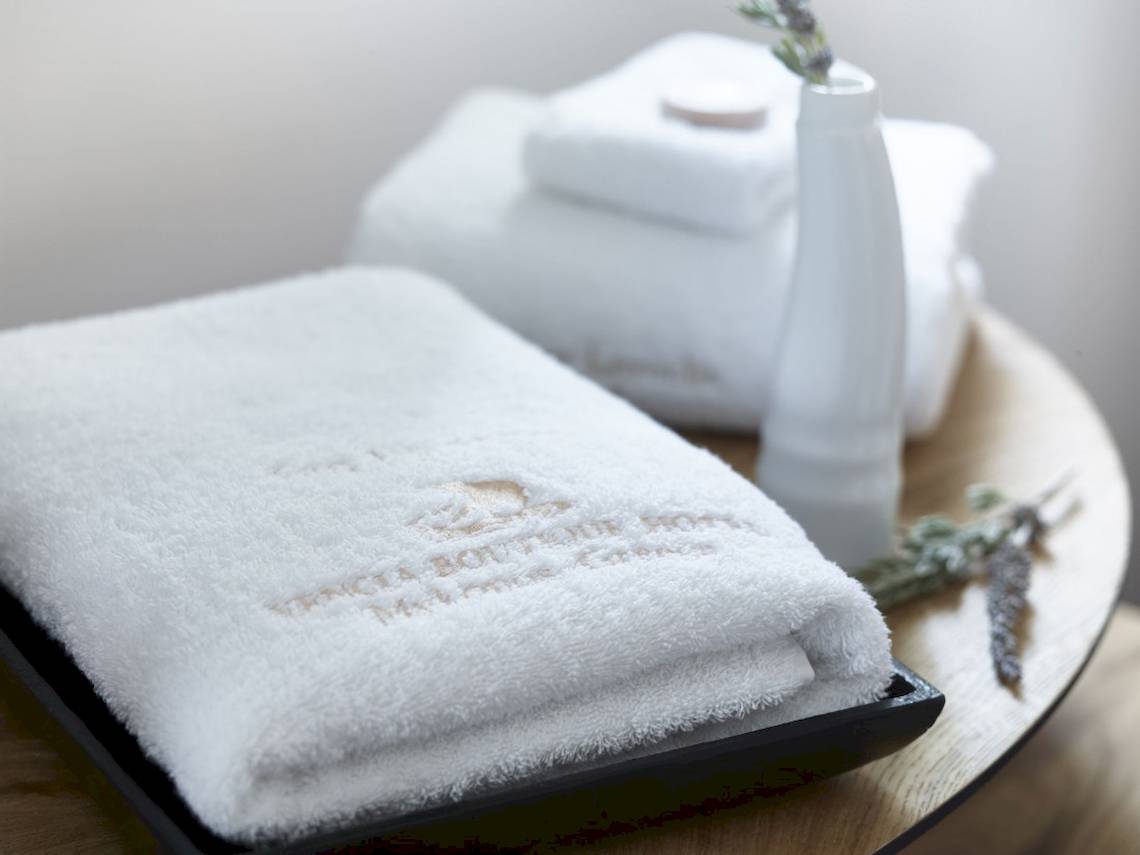 Vencia Boutique Hotel Handtücher auf einem Tisch, umgeben von Lavendel und einer Vase.