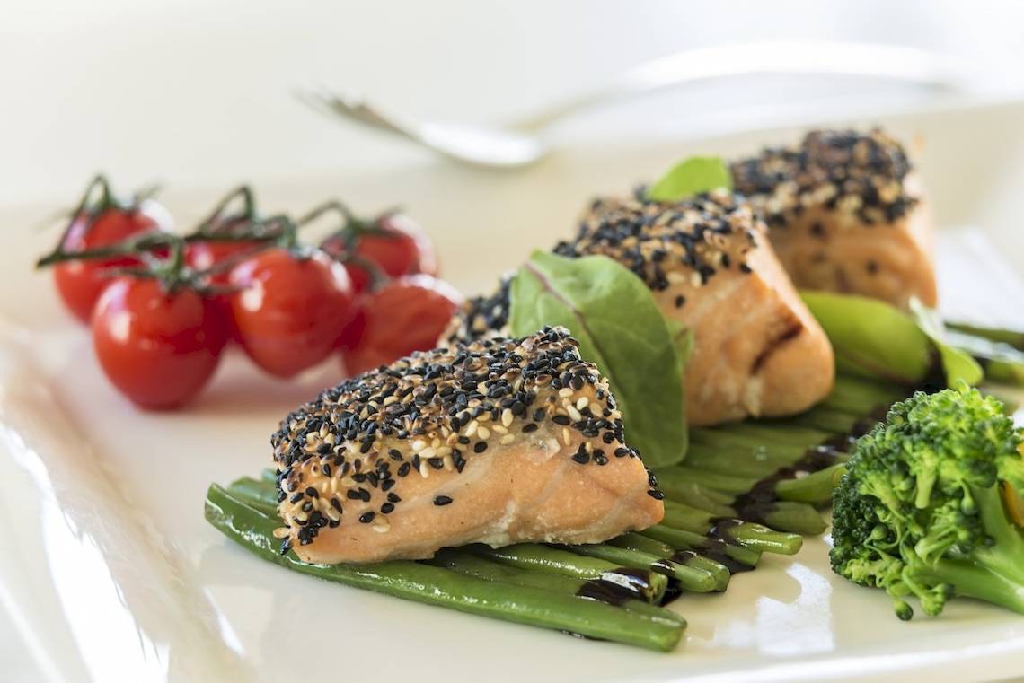 Portion Lachs auf einem Teller mit Gemüse und Kirschtomaten