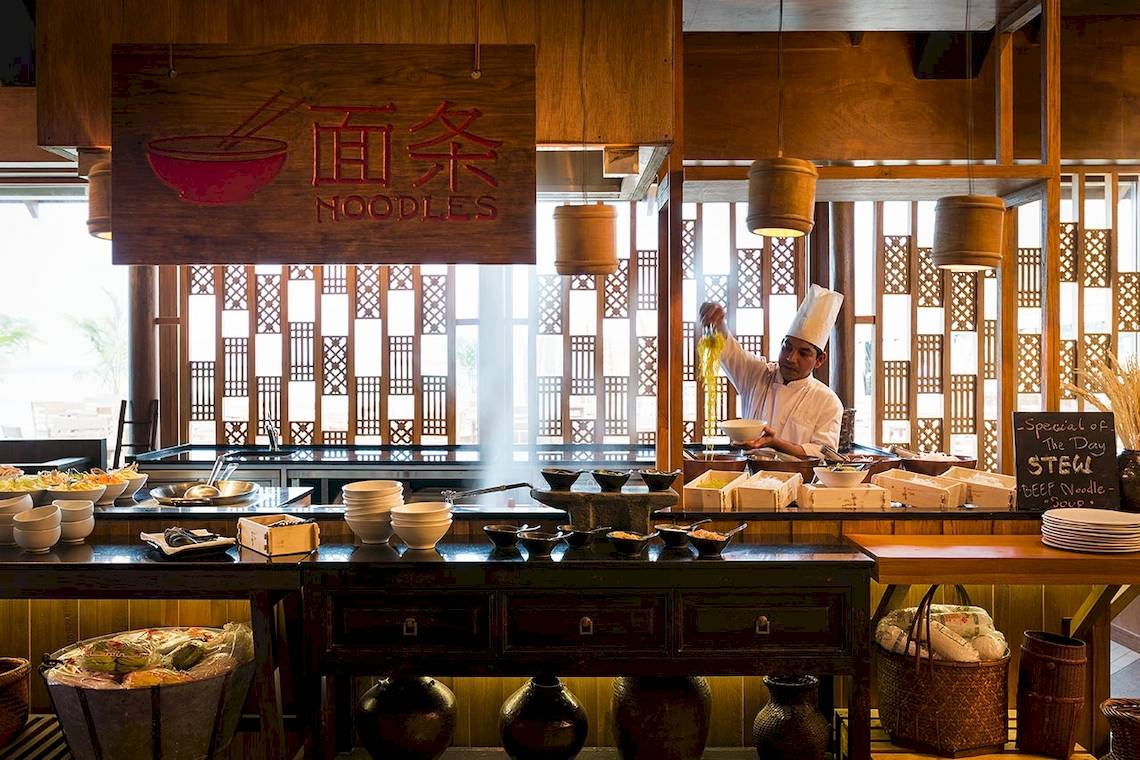 Innenansicht des Nudelrestaurants im LUX South Ari Atoll Hotel mit Köchen und Speisen.