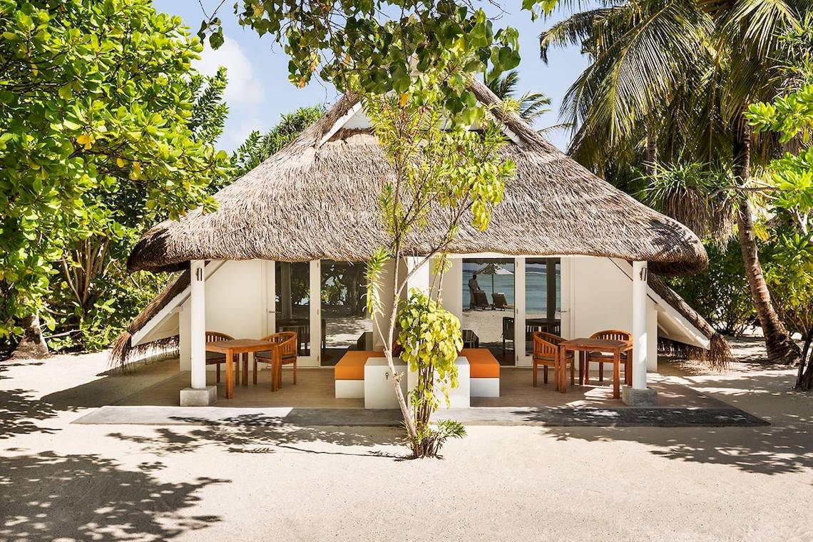 Strandhütte im LUX South Ari Atoll Hotel mit Meerblick und Möbeln auf der Veranda.