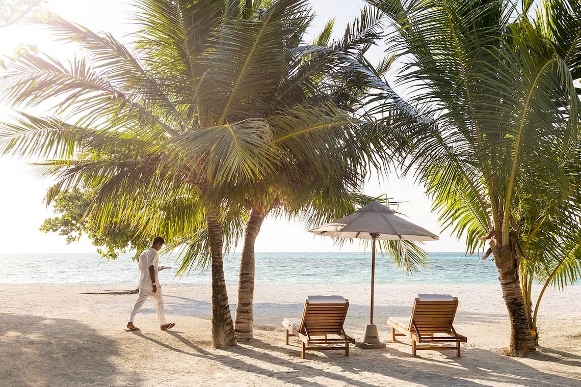 Strand mit Palmen und Sonnenschirmen am LUX South Ari Atoll