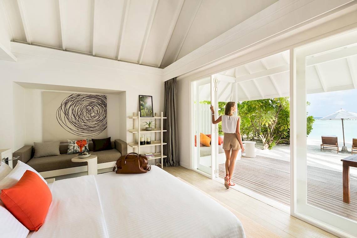 Innenansicht eines Schlafzimmers im LUX South Ari Atoll Hotel mit Blick auf den Garten und das Meer.