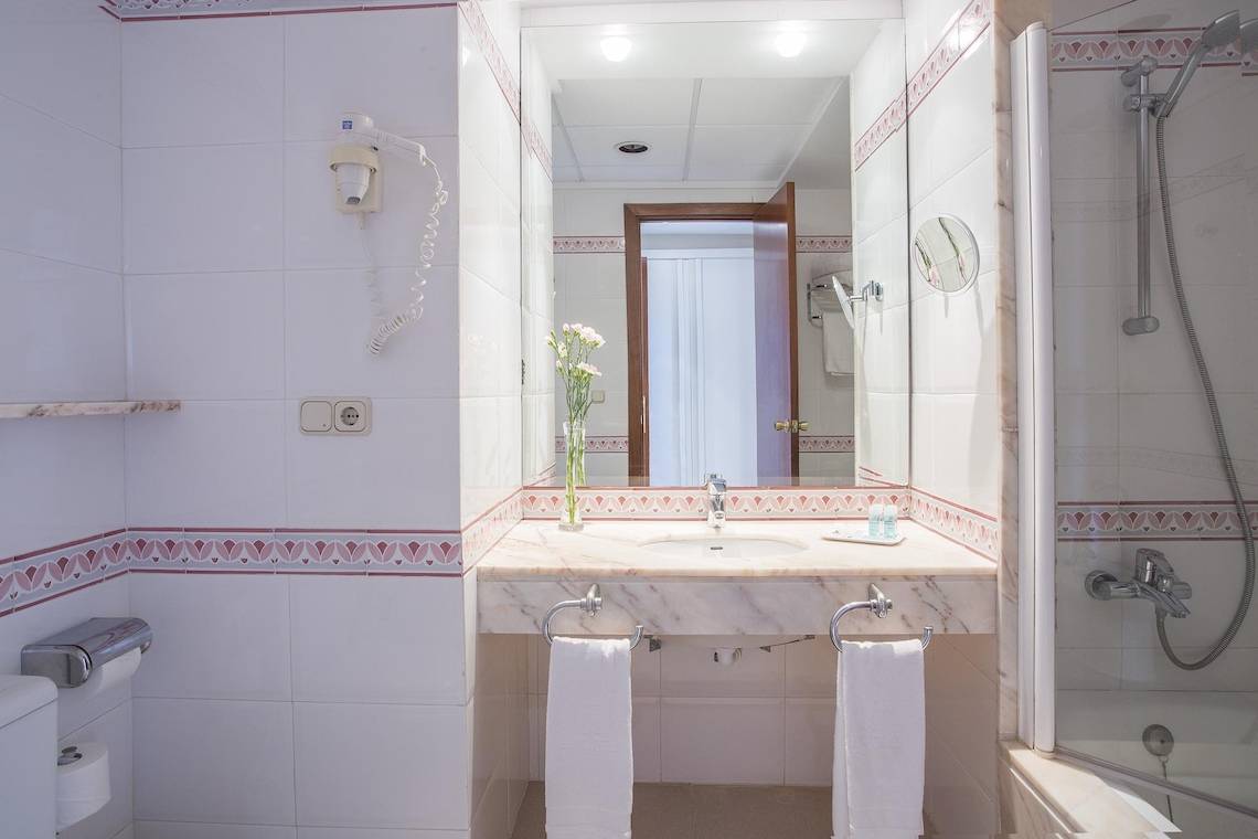 Badezimmer im Hipotels Said Hotel mit weißem Waschbecken, Spiegel und Handtüchern.