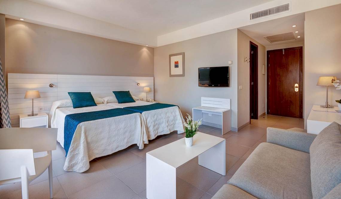 Schlafzimmer im Hipotels Said Hotel mit zwei Betten, Fernseher und Wohnzimmerecke.
