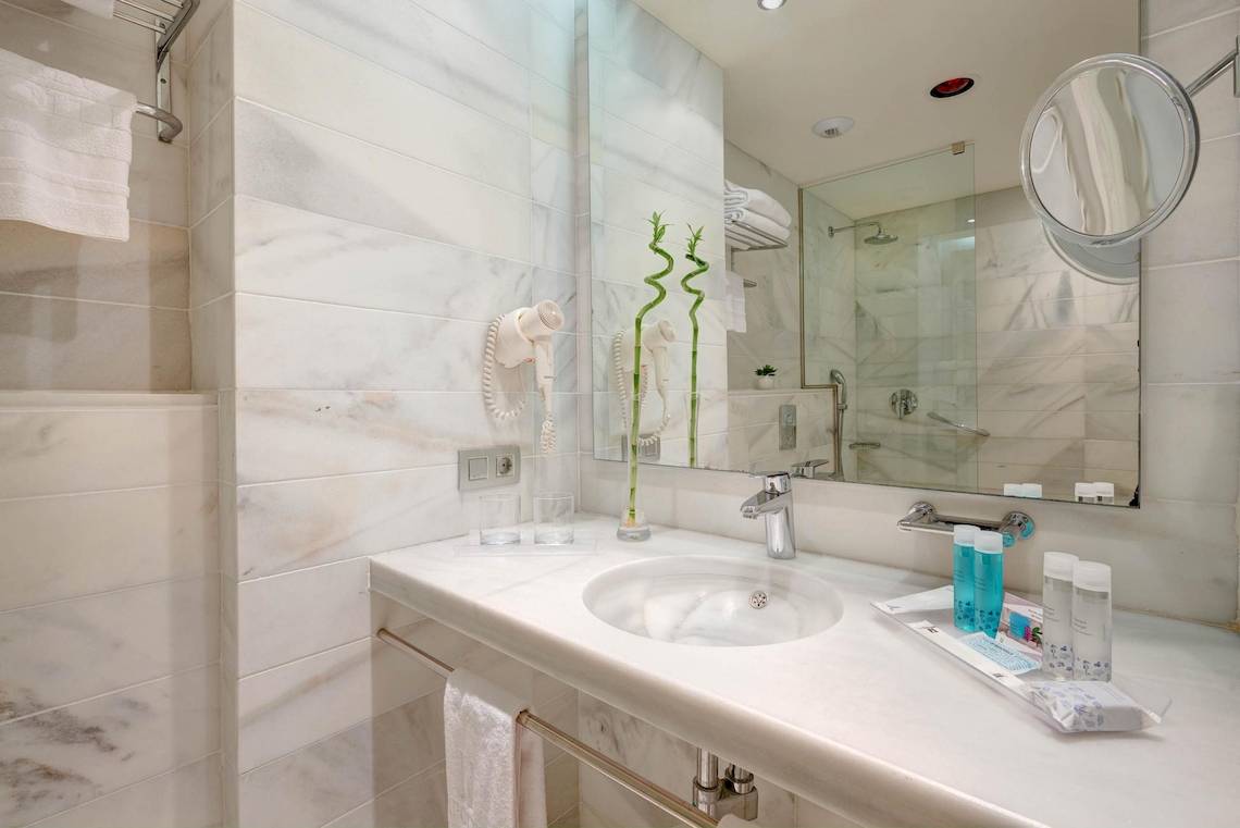 Badezimmer des Hipotels Said mit weißem Marmor, Spiegel und Toilettenartikeln