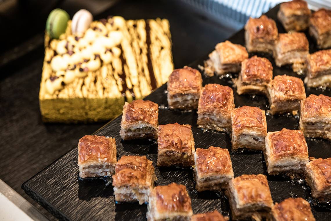 Nahaufnahme von verschiedenen Desserts im Avra Imperial Hotel, darunter eine Tarte und viele kleine Gebäckstücke.