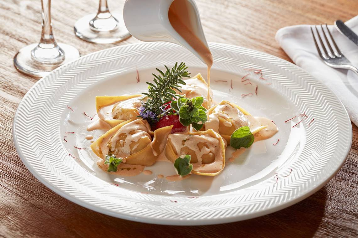 Ein Teller mit gefüllten Ravioli auf dem Avra Imperial Hotel serviert wird.