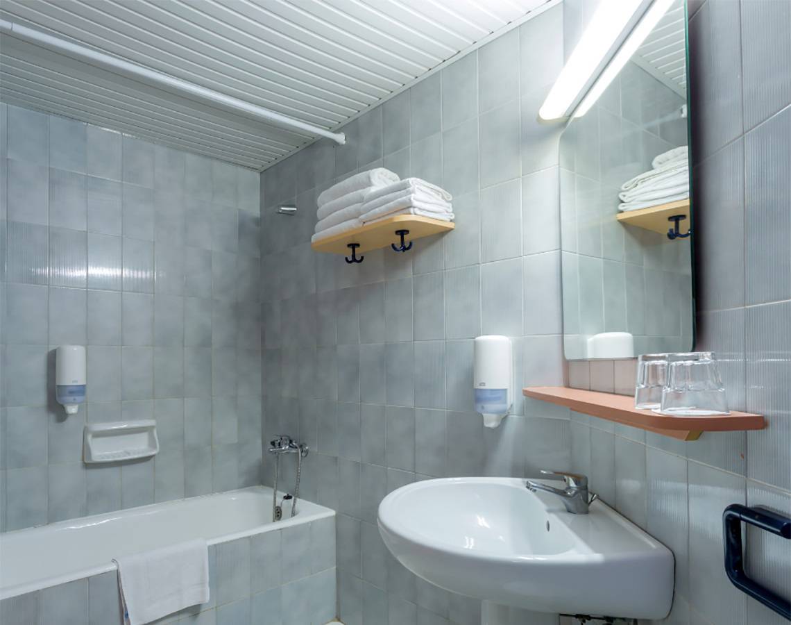 Badezimmer im Dessole Dolphin Bay Resort mit Badewanne, Waschbecken, Spiegel und Handtüchern