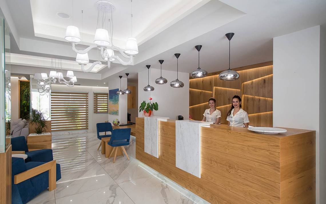 Rezeption des Odyssia Beach Hotels mit zwei lächelnden Mitarbeiterinnen im Vordergrund.