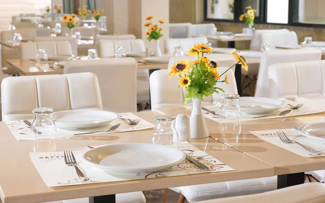Restauranttisch im Odyssia Beach Hotel, dekoriert mit Sonnenblumen in einer Vase.