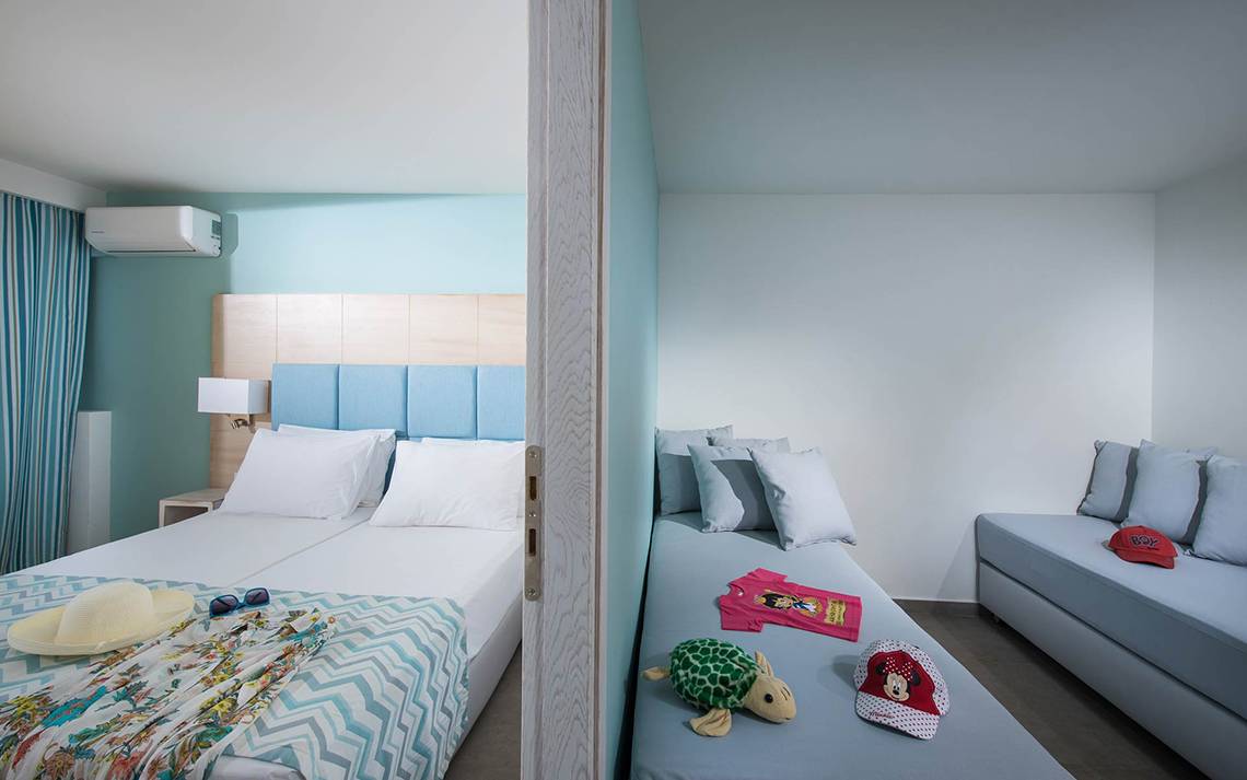 Doppelzimmer-Innenansicht im Odyssia Beach Hotel mit zwei Betten, blauen Wänden und hellem Dekor.