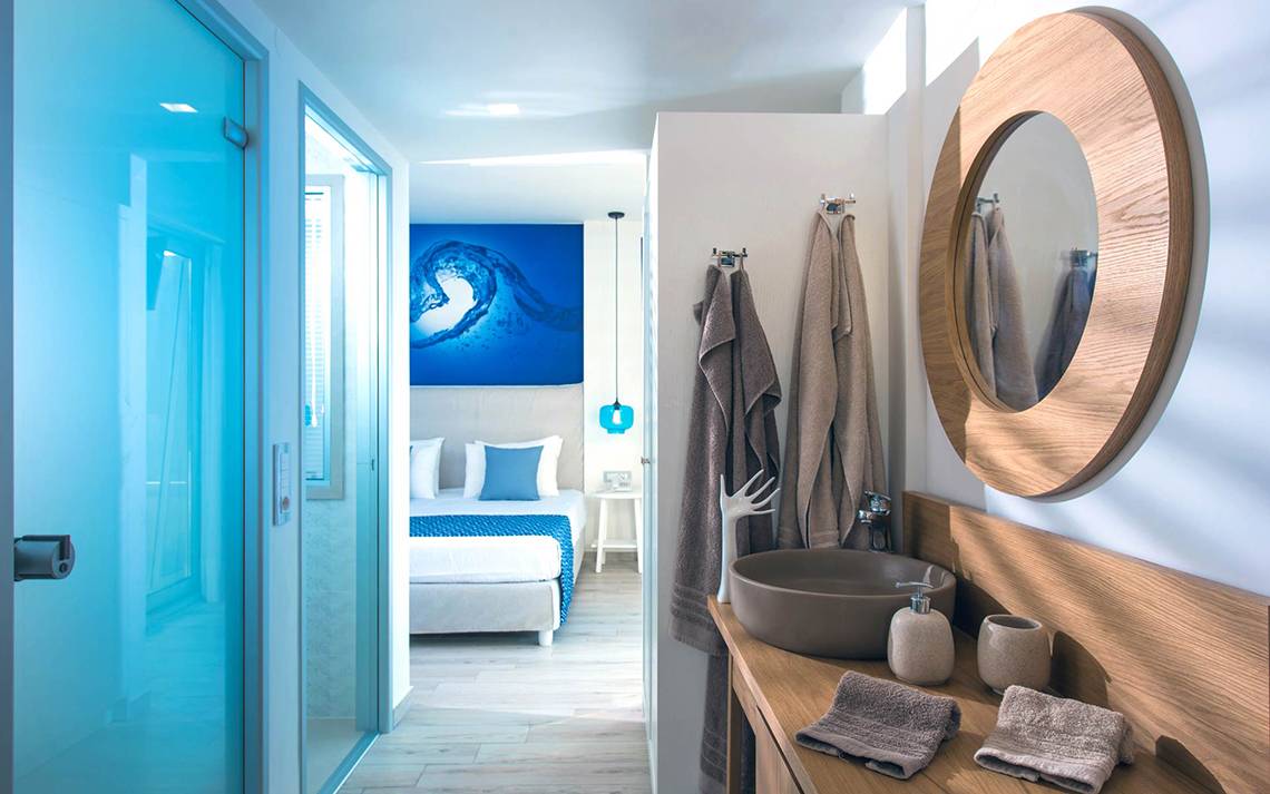 Badezimmer im Odyssia Beach Hotel mit Blick auf das Bett und eine blaue Wand.