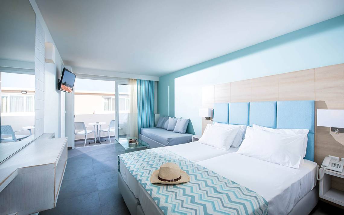 Innenansicht eines Zimmers im Odyssia Beach Hotel mit Doppelbett, Sofa, Fernseher und Balkon