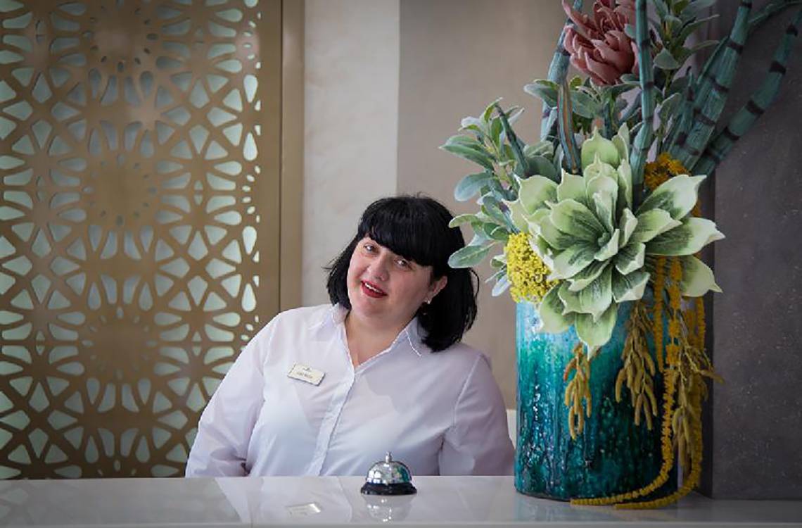 Rezeptionistin des Stamatia Hotels lächelt vor einem Blumenarrangement