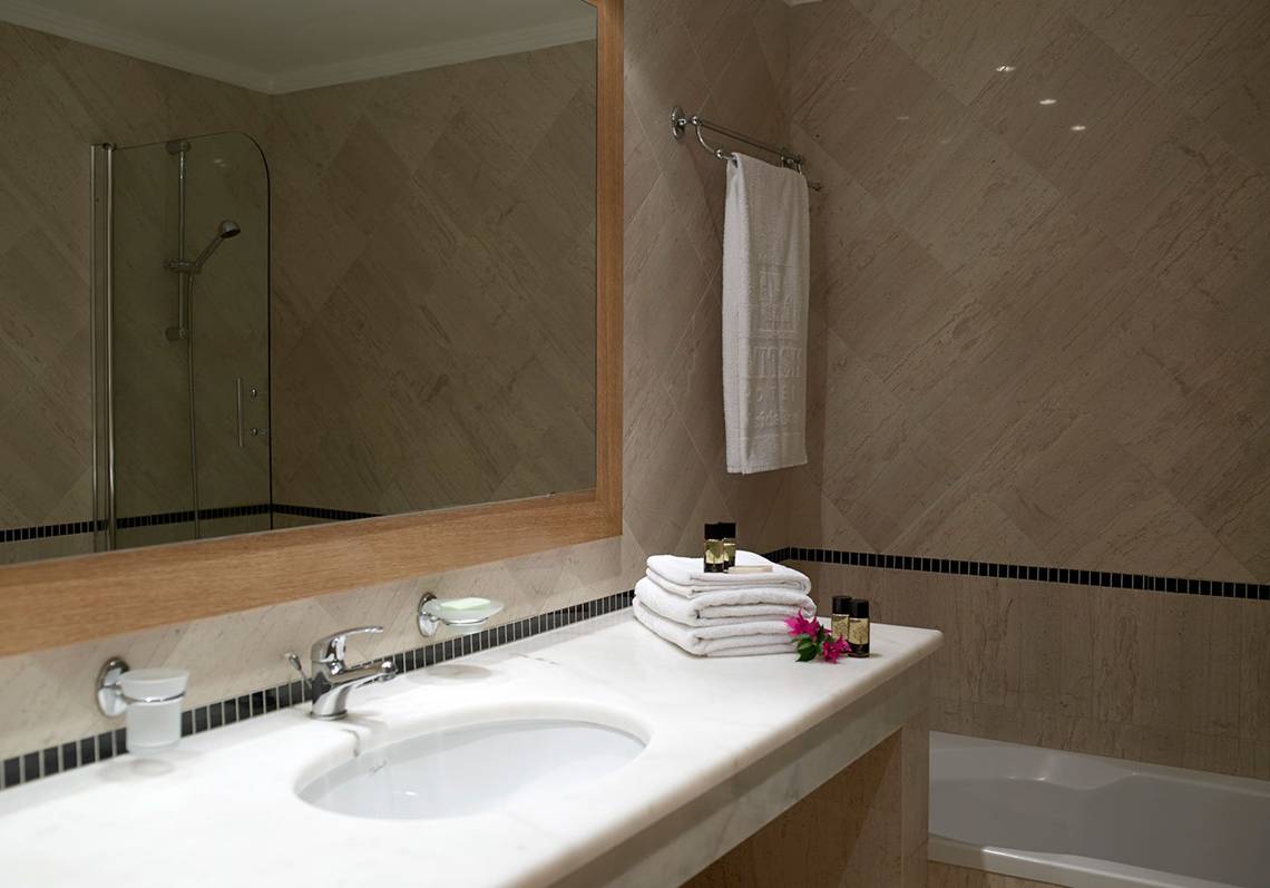 Badezimmer im Mitsis Norida Beach Hotel mit Spiegel, Handtüchern, Flüssigseifen und Badewanne