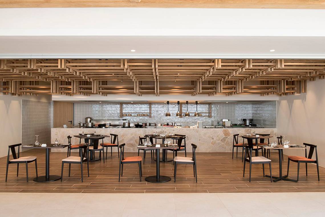 Innenansicht des Restaurants im Mitsis Norida Beach Hotel mit Holzboden und modernen Möbeln.