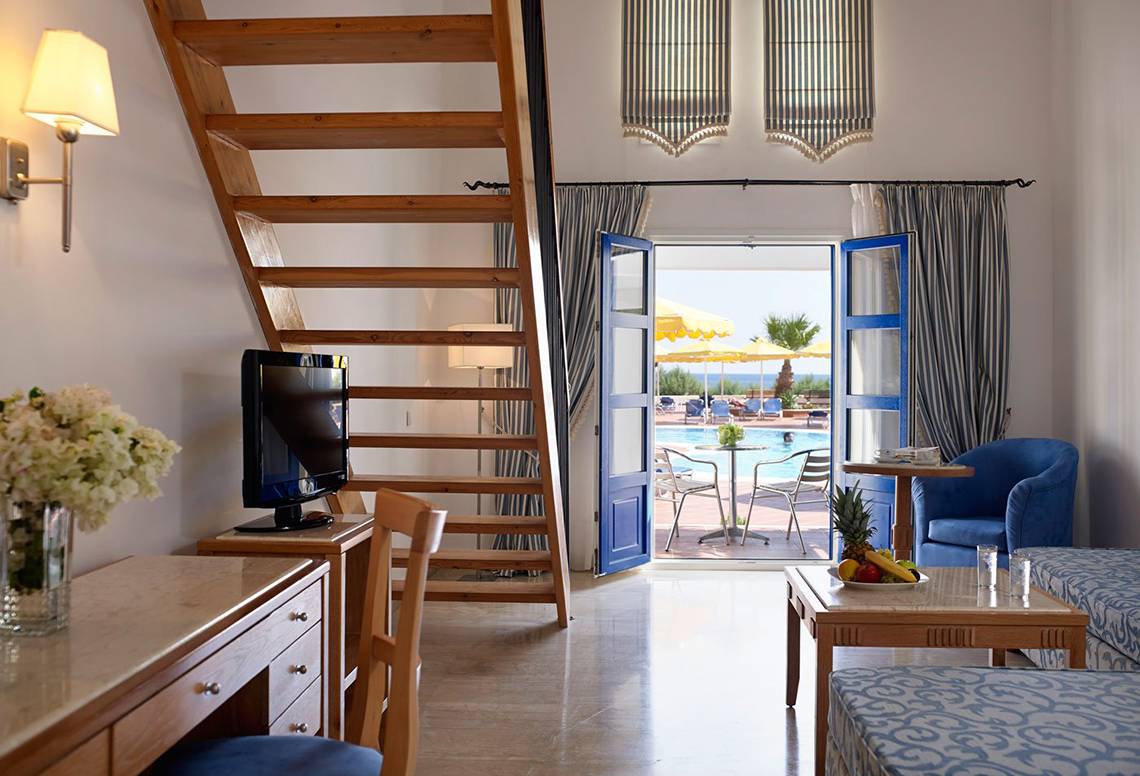 Innenansicht eines Zimmers im Mitsis Norida Beach Hotel mit Blick auf einen Swimmingpool.
