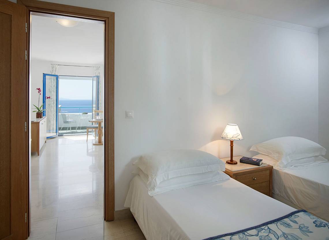 Zimmer im Mitsis Norida Beach Hotel mit Blick auf das Meer von einer Terrasse.