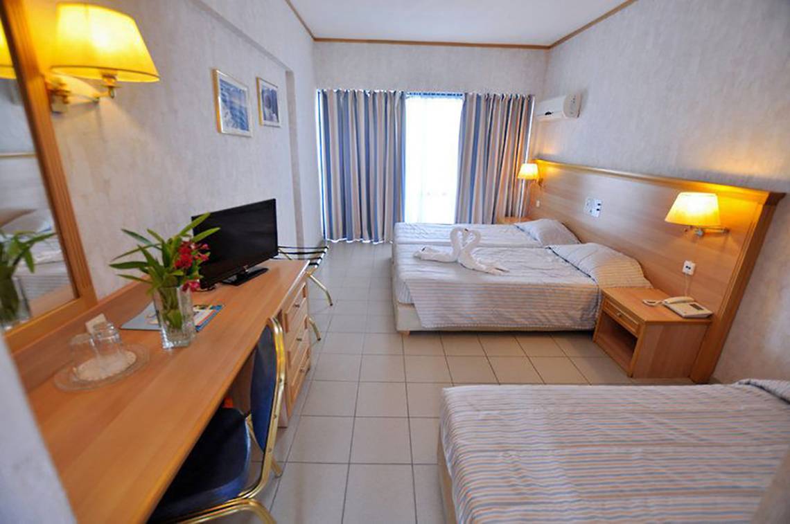 Hotelzimmer des Smy Kos Beach & Splash mit zwei Betten, Fernseher, Schreibtisch und Spiegel.