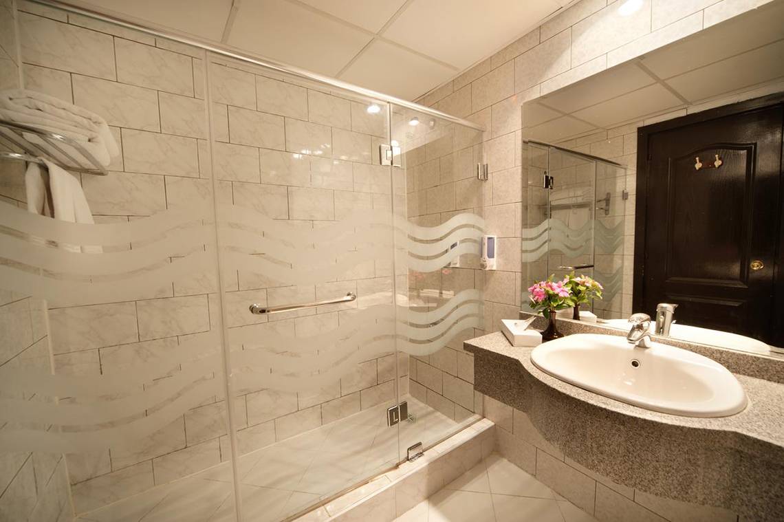 Badezimmer im Ali Baba Palace Hotel mit geschwungener Duschkabine und Waschbecken.