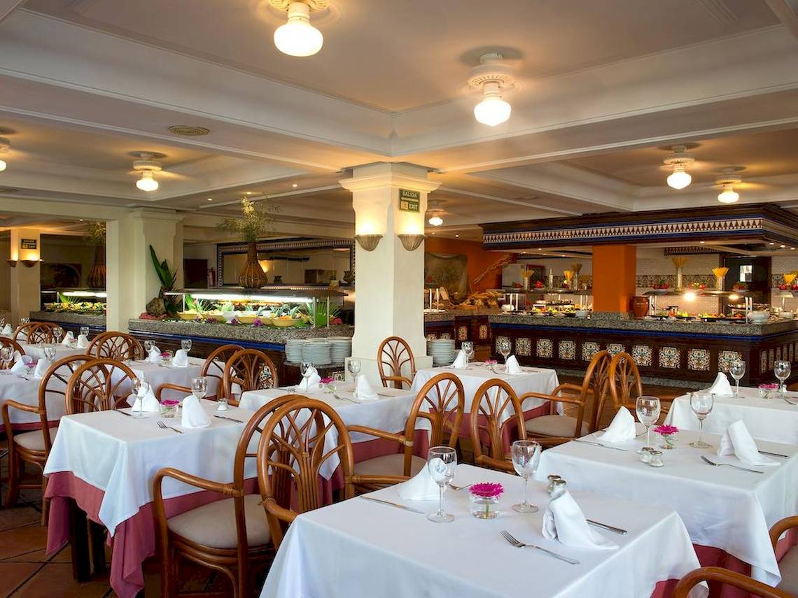 Eines der Restaurants im Bluebay Banus Hotel mit gedeckten Tischen und Buffet im Hintergrund.