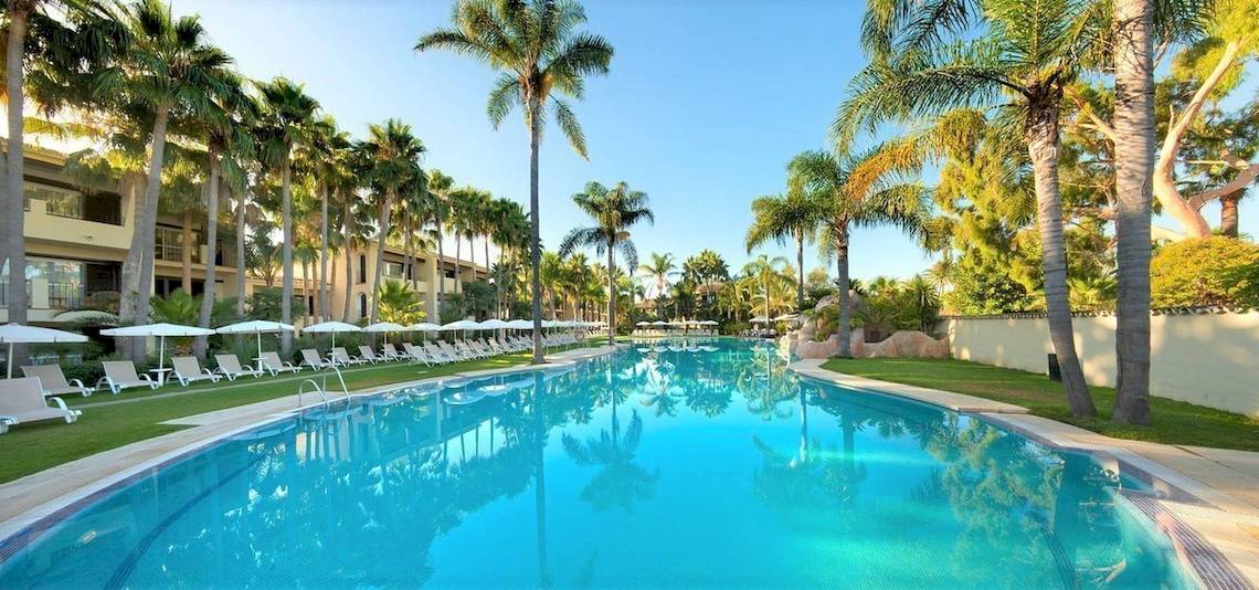 Außenpool des Bluebay Banus Hotels mit Liegestühlen und Palmen
