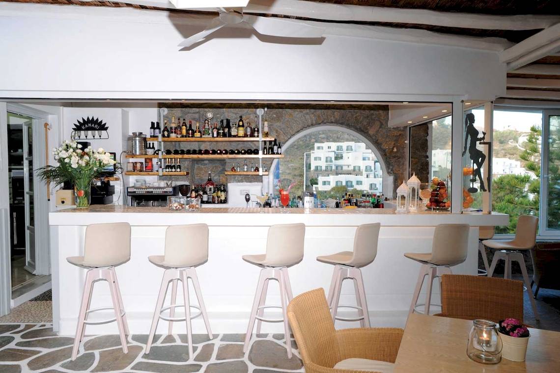 Rezeption des Kamari Hotels mit Bar, Stühlen und Tischen, Blick auf ein Gebäude und Landschaft