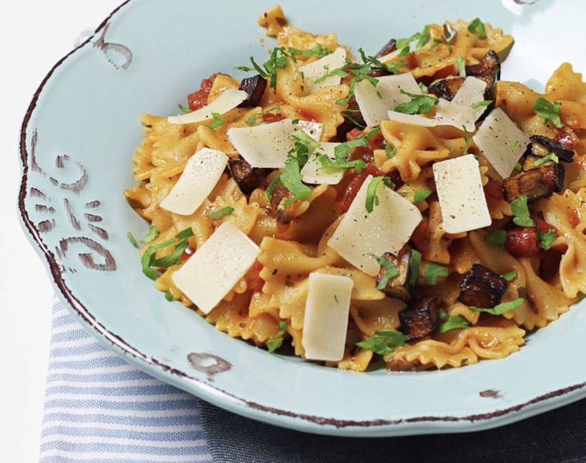 Nahaufnahme von Pasta mit Pilzen und Tomaten auf einem blauen Teller