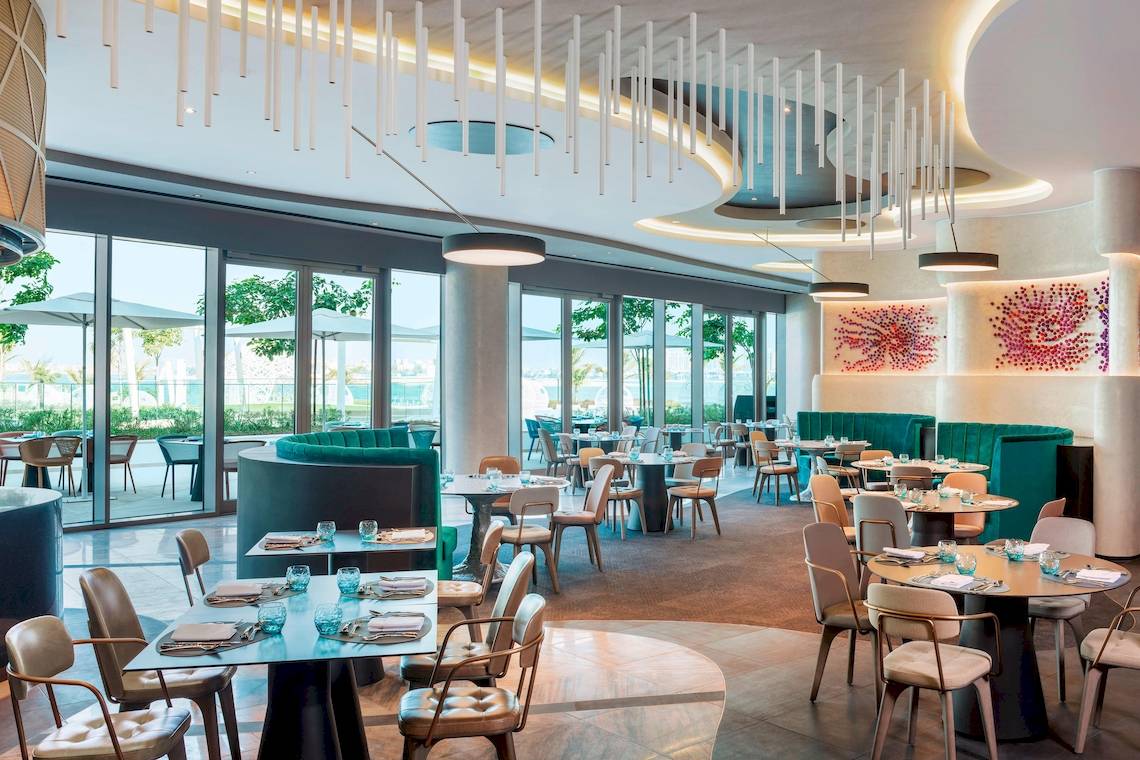 Innenansicht des Restaurants im W Dubai - The Palm mit modernen Möbeln und Glaswänden.