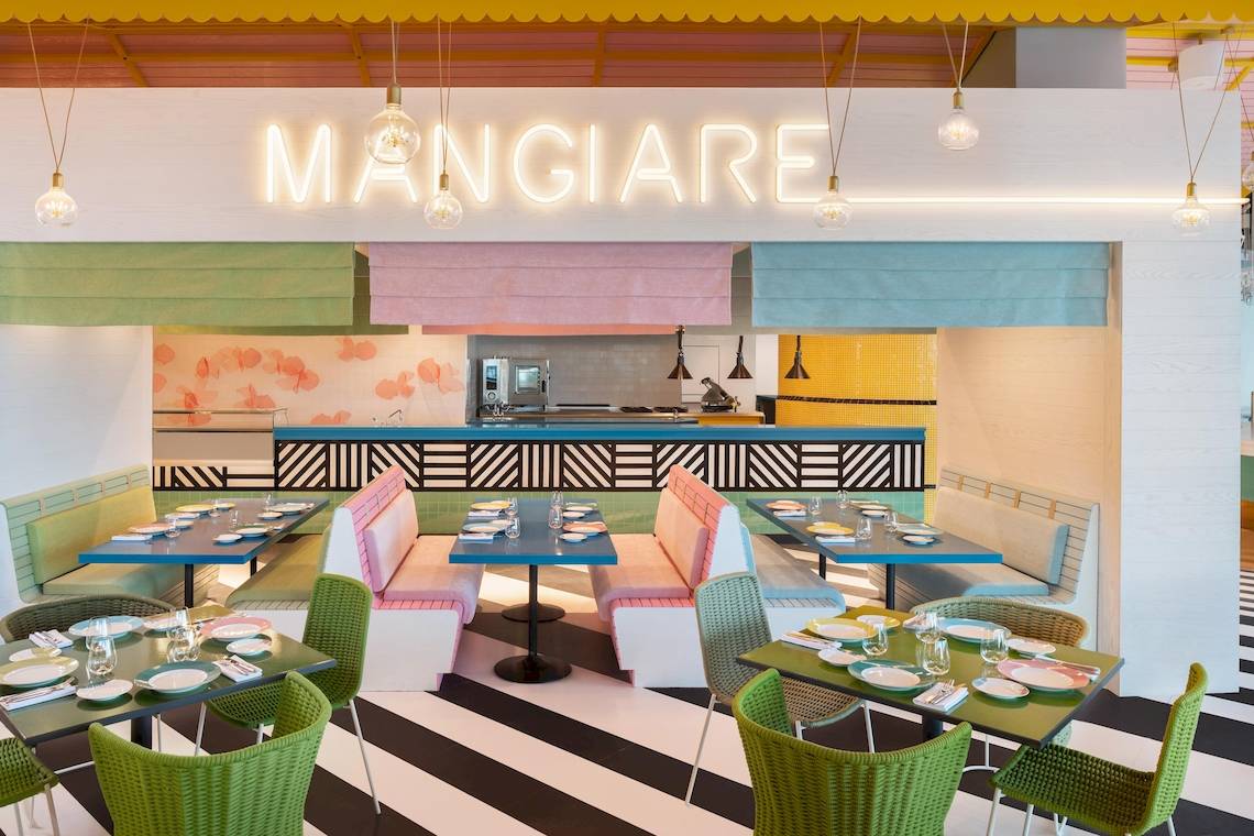 Innenansicht des Mangiare Restaurants im W Dubai - The Palm mit farbenfrohen Sitzbänken und Tischen.