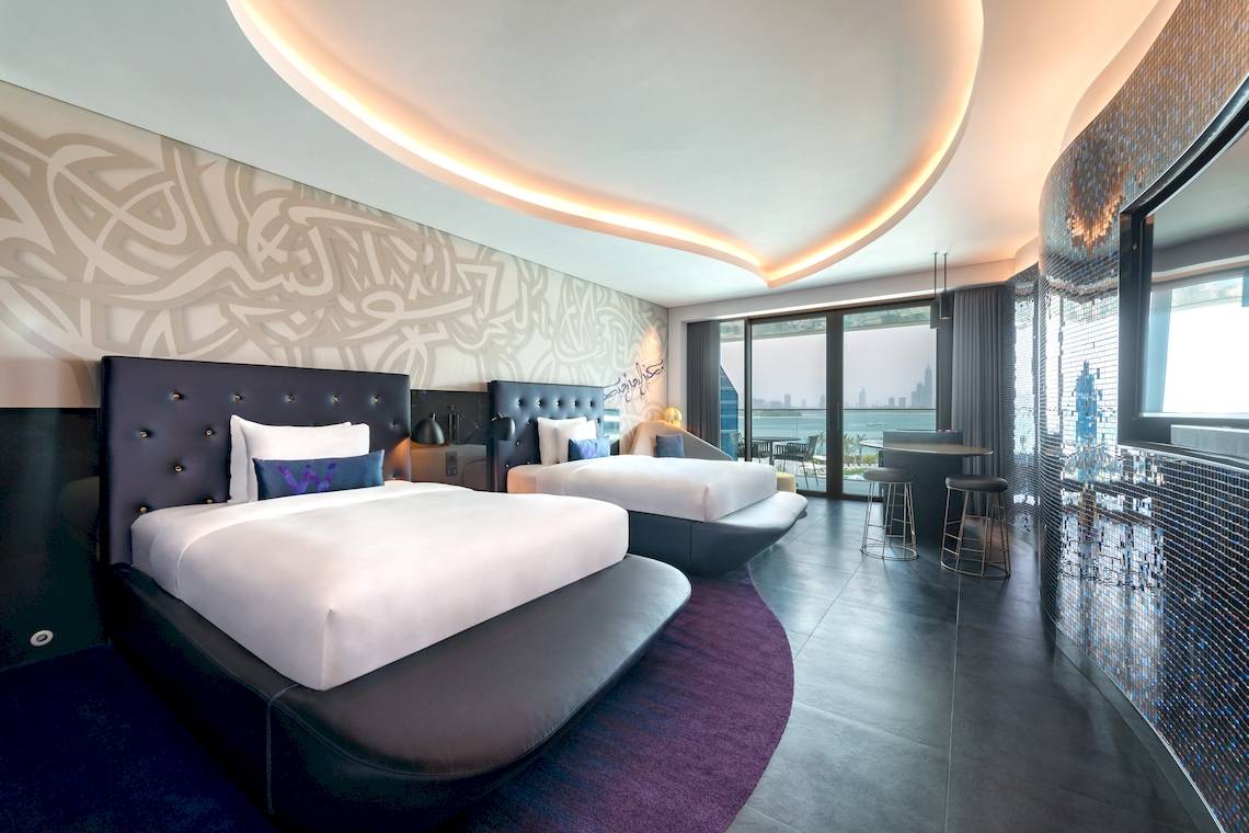 Schlafzimmer im W Dubai - The Palm Hotel mit zwei Betten, modernen Möbeln und Blick auf den Ozean.