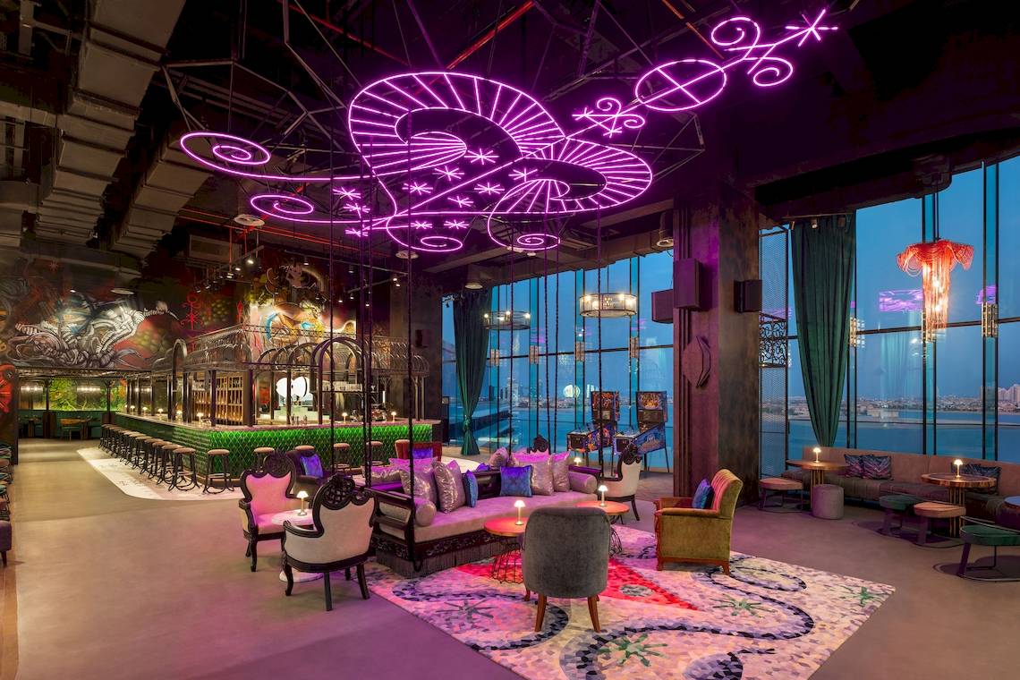 Loungebereich des W Dubai - The Palm Hotels mit bunten Möbeln und Deckenleuchten.