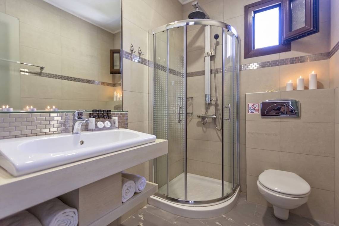 Badezimmer mit Dusche, Toilette, Waschbecken und Kerzen.