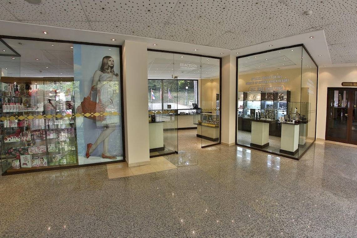 Eingangsbereich des Riviera Beach Hotels mit Werbeplakat und Geschäften