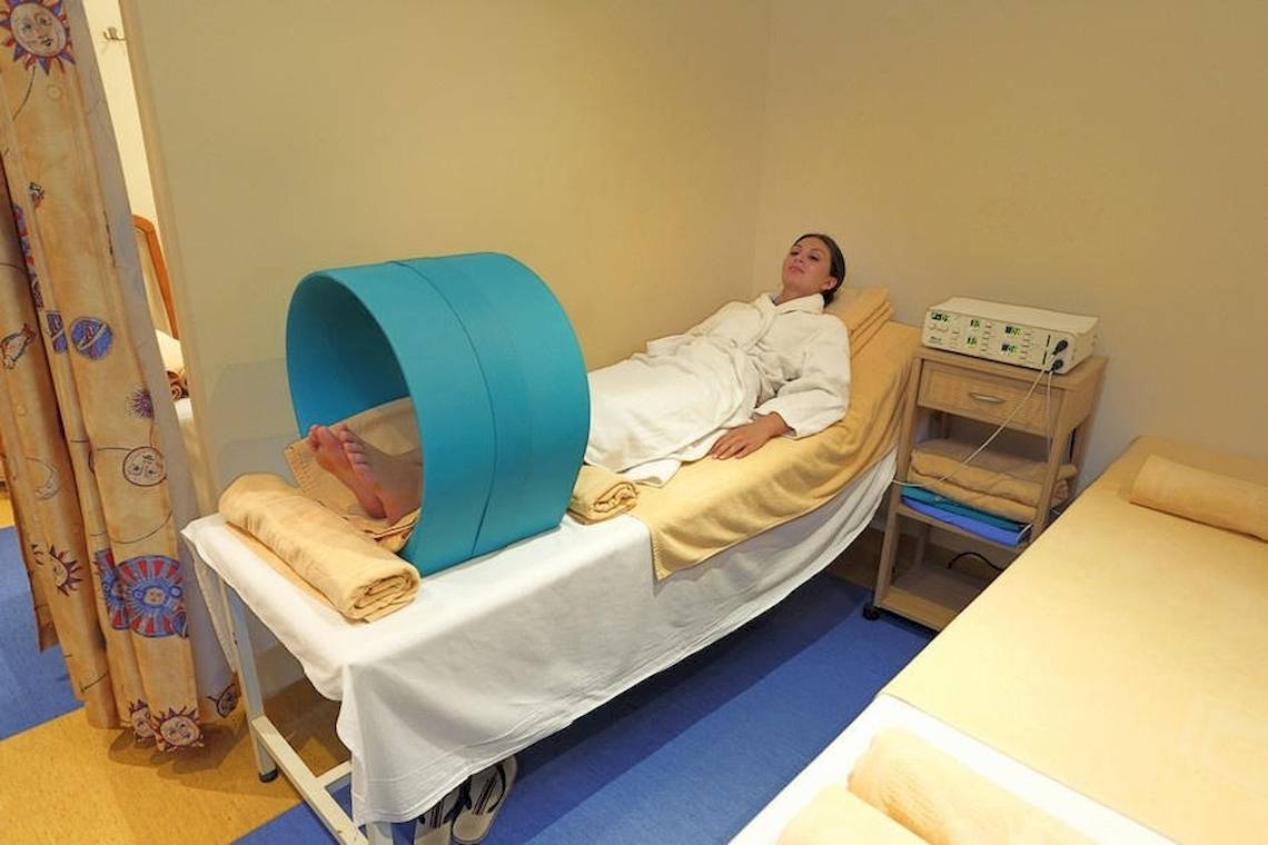Eine Frau im Spa-Bereich des Riviera Beach Hotels liegt auf einem Bett mit einer blauen Liegehilfe.
