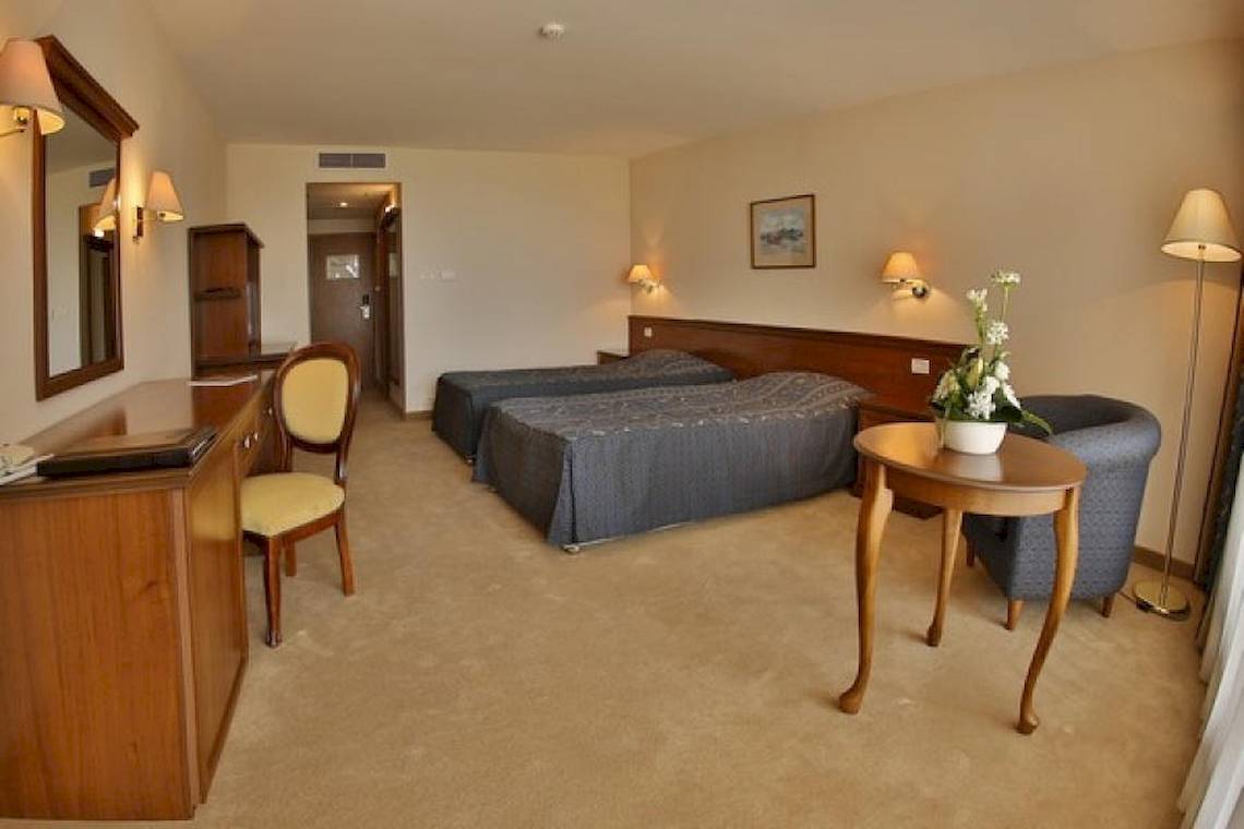Doppelzimmer im Riviera Beach Hotel mit zwei Betten, Schreibtisch, Spiegel und Beleuchtung.