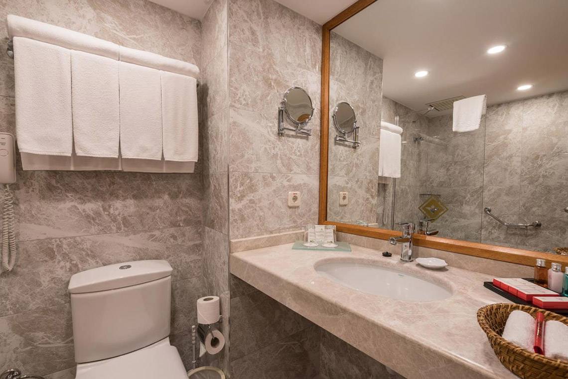 Badezimmer im Miramare Queen Hotel mit Toilette, Waschbecken, Spiegel und Handtüchern.