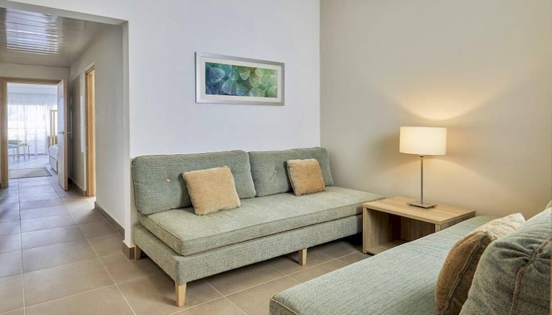 Hotelzimmer im Jaz Maraya Resort mit grünem Sofa, Tischlampe und Gemälde an der Wand.