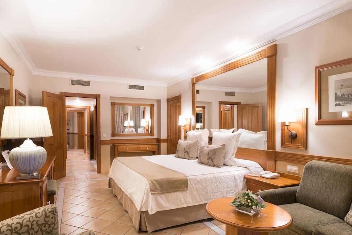 Schlafzimmer im GF Gran Costa Adeje Hotel mit großem Bett, Spiegel, Lampe und Dekor