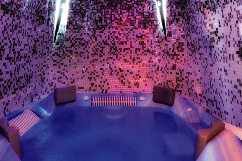 Ein Whirlpool im Saudade Hotel mit violetten und rosafarbenen Kacheln und blauem Wasser.