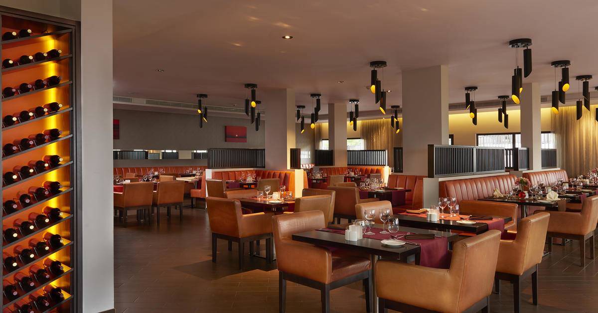 Innenansicht des Restaurants im Melia Dunas Beach Resort & Spa mit gepolsterten Stühlen und Tischen.