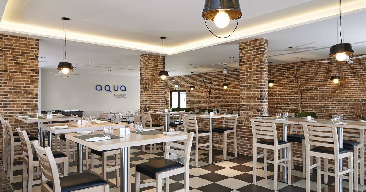 Innenansicht des Aqua Restaurants im Melia Dunas Beach Resort & Spa mit gemustertem Boden und Ziegelwänden.