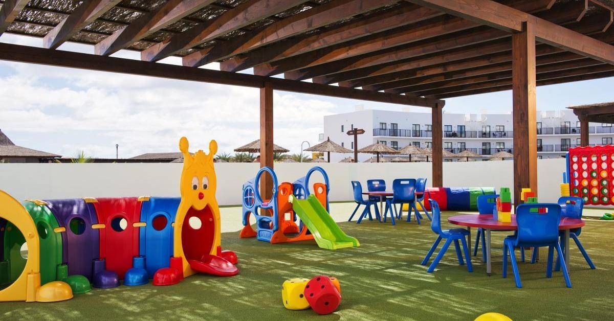 Kinderspielplatz im Melia Dunas Beach Resort & Spa mit bunten Spielgeräten und einem grünen Spielbereich.