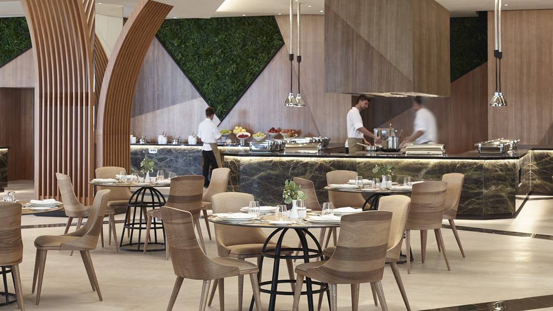 Innenraum des Mayia Exclusive Resort & Spa mit gepflegten Tischen und Stühlen, Mitarbeitern hinter der Theke.
