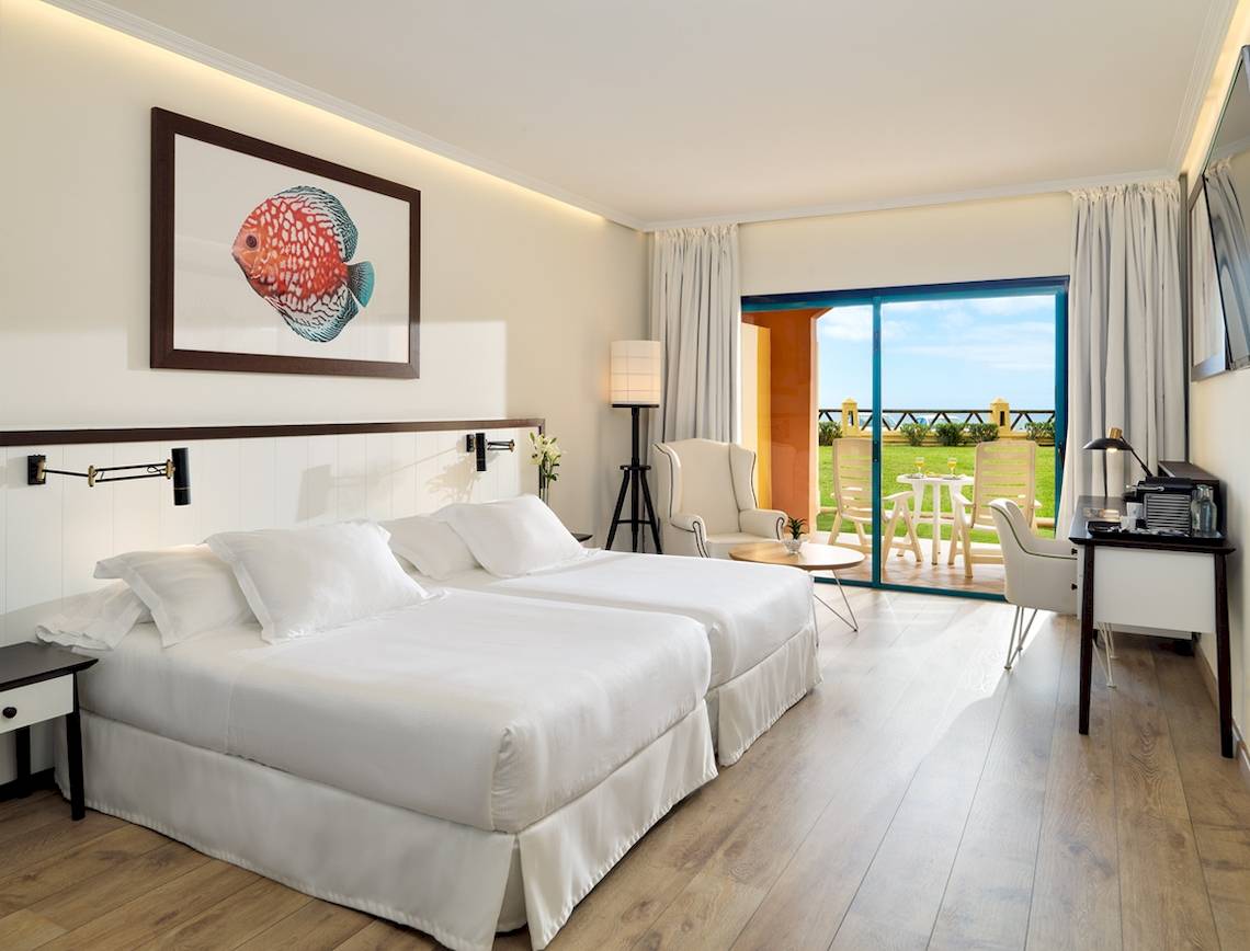 Innenansicht eines Doppelzimmers im H10 Playa Esmeralda Hotel mit zwei Betten und einem Balkon.