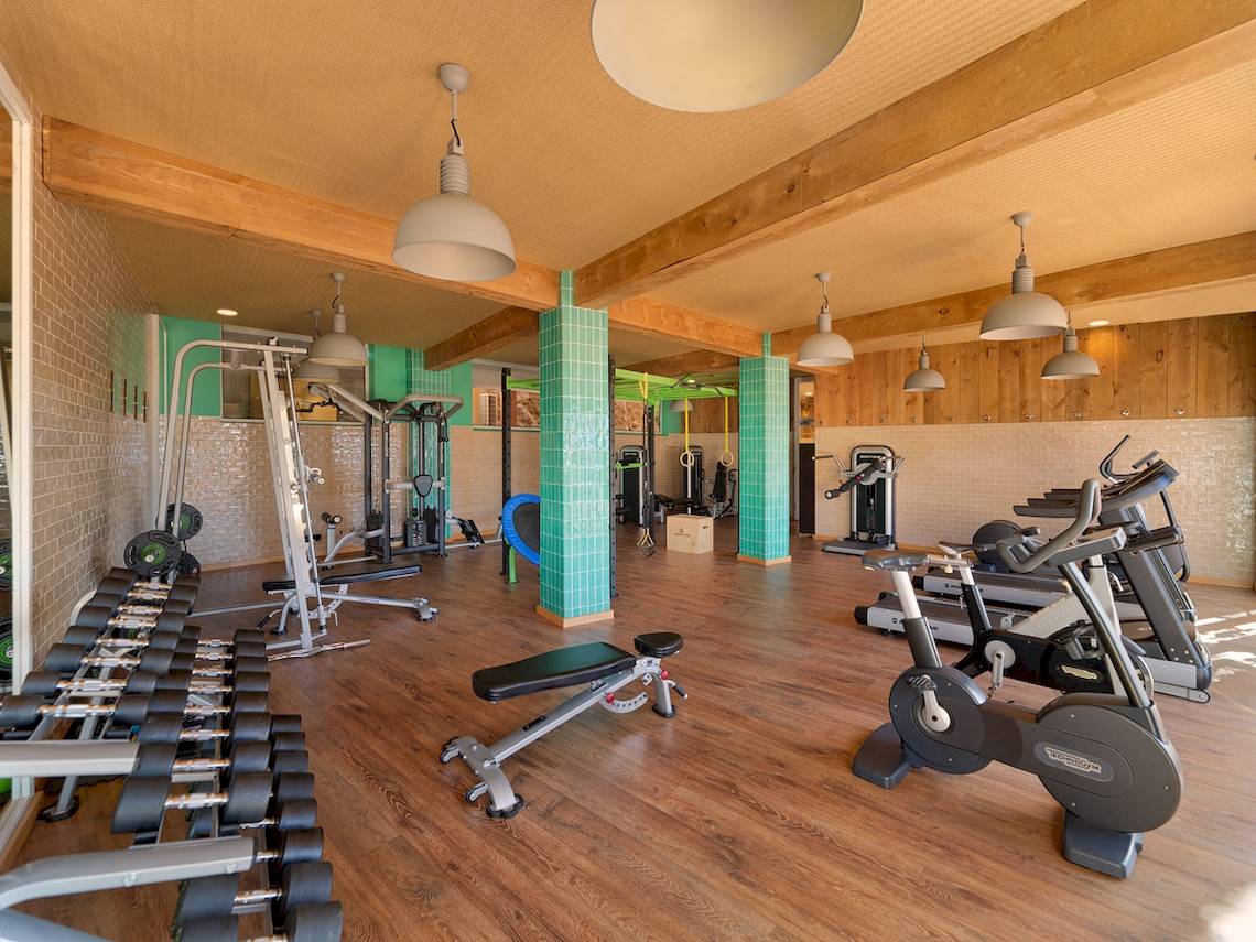 Fitnessstudio im H10 Playa Esmeralda Hotel mit verschiedenen Geräten und Holzboden.