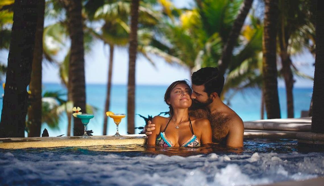 Paar im Pool beim Catalonia Royal Tulum Hotel mit Blick auf den Ozean und Palmen