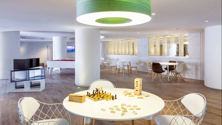 Spielzimmer des Tigotan Lovers & Friends Hotel mit Tischspielen, Sofas und weißer Inneneinrichtung.