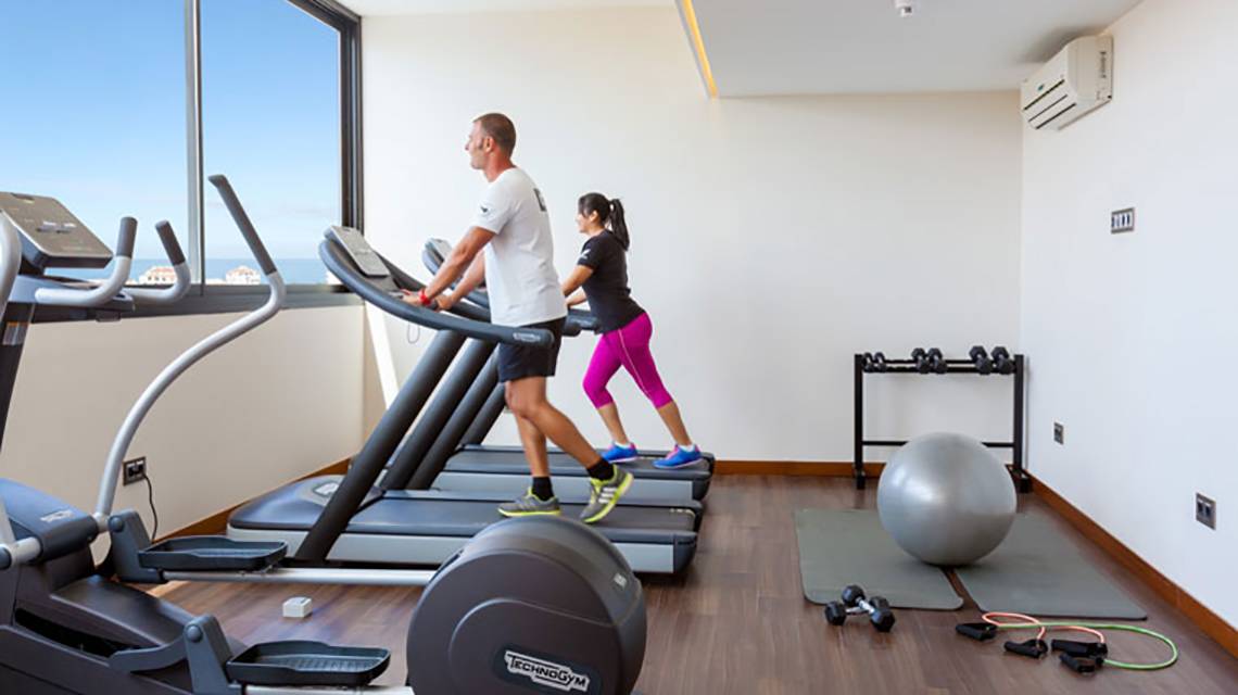Zwei Personen laufen auf dem Laufband im Fitnessstudio des Tigotan Lovers & Friends Hotels.
